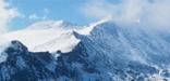 The snow-covered ridgeline from Longs Peak to Pagoda Mountain partly obscured by wisps of cloud. (NPS Photo)