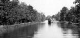 Coal Cargo Boat in the middle of the Canal being pulled by a mule team on the right hand side.